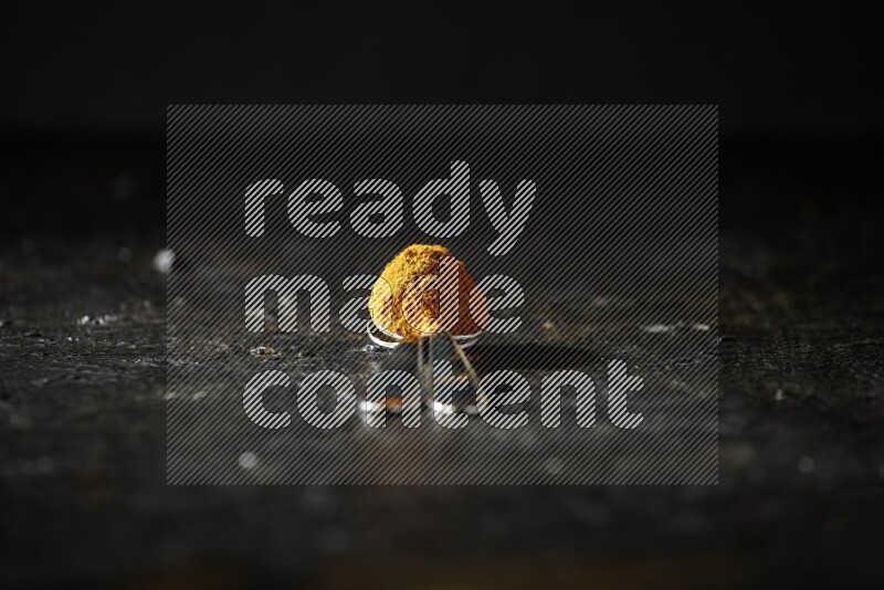 ملعقتان معدنيتان ممتلئتان ببودرة الكركم على خلفية سوداء