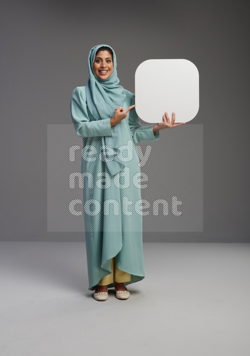 Saudi Woman wearing Abaya standing holding social media sign on Gray background