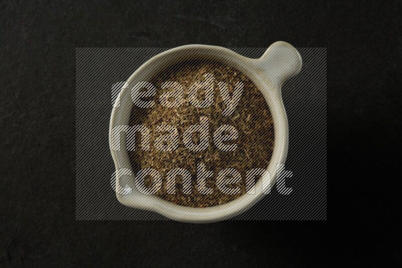 multi color round sauce bowl filled with herbs on grey textured countertop