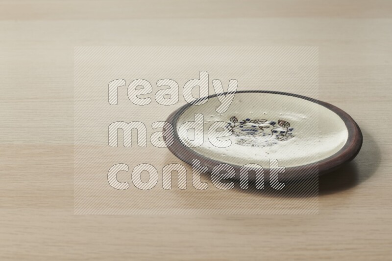 A decorative pottery plate on light wooden background