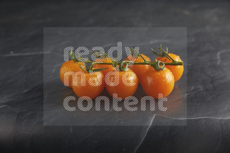 Orange cherry tomato vein on a textured black slate background 45 degree
