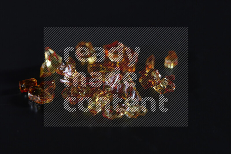 Transparent orange fragments of glass scattered on a black background