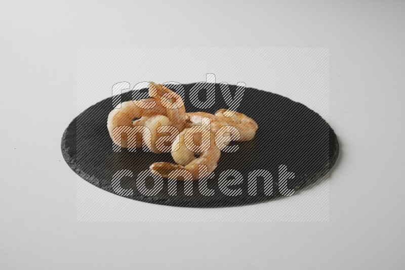 five grilled shrimps  on a black slate direct  on a white back ground