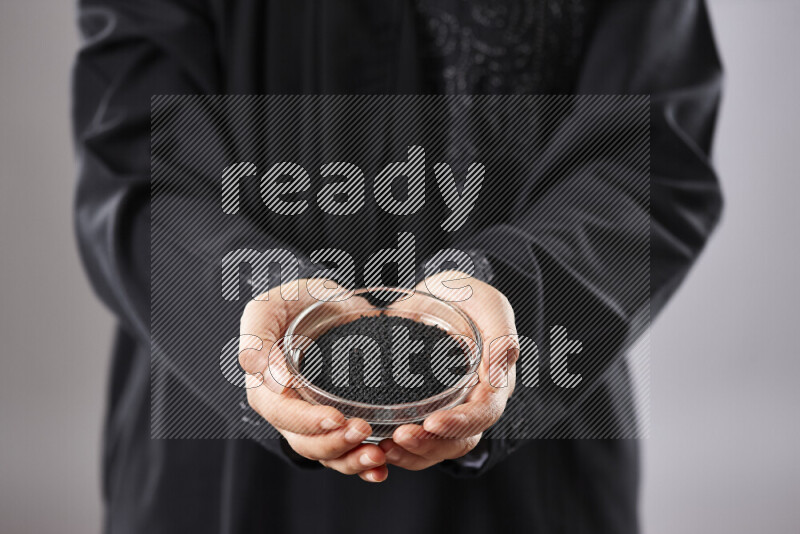 Woman in abaya holding different kinds of spices in different positions