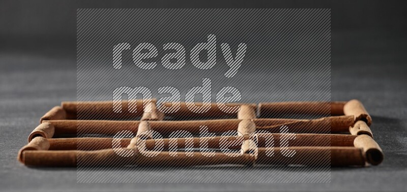 9 empty squares of cinnamon sticks on black flooring