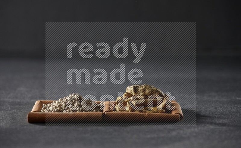 2 squares of cinnamon sticks full of white pepper and turmeric fingers on black flooring