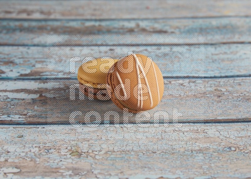 45º Shot of of two assorted Brown Irish Cream, and Yellow, and Brown Chai Latte macarons  on light blue background
