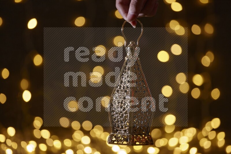 A traditional ramadan lantern surrounded by glowing fairy lights in a dark setup
