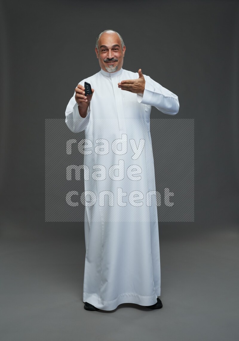 Saudi man without shomag Standing holding car key on gray background