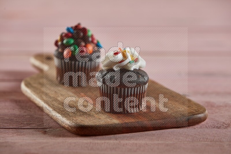 Chocolate mini cupcake topped with cream on a wooden board