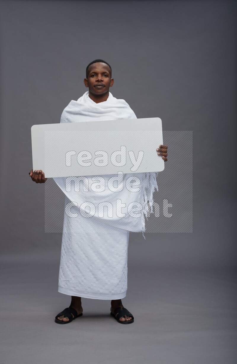 A man wearing Ehram Standing holding board sign on gray background
