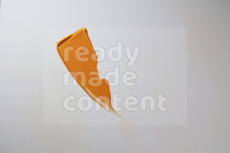 An orange single curved painting knife stroke on white background