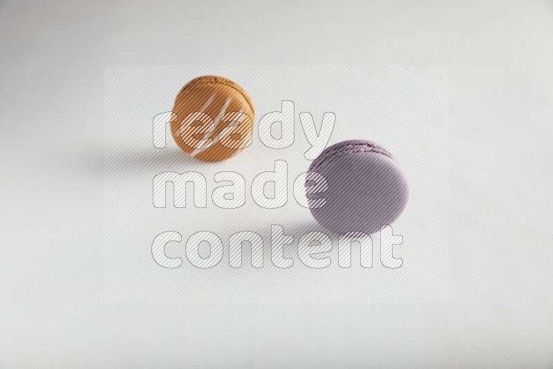 45º Shot of of two assorted Brown Irish Cream, and Purple Blueberry macarons on white background