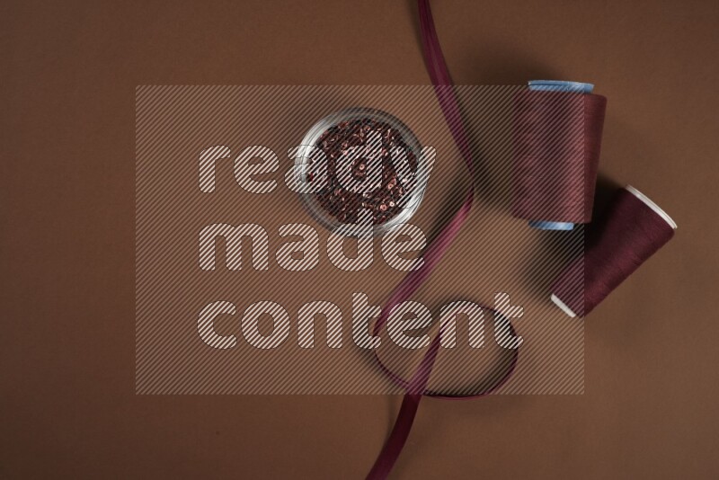 A red collection of sewing and tailoring tools arranged on a brown background