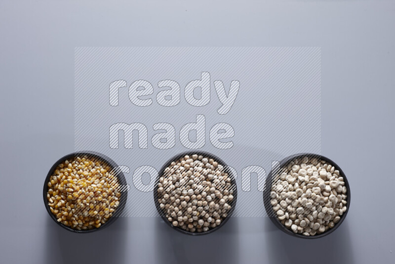 Legumes in pottery bowls on light grey background