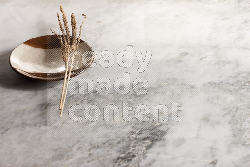 Wheat stalks on multicolored pottery plate on grey marble background