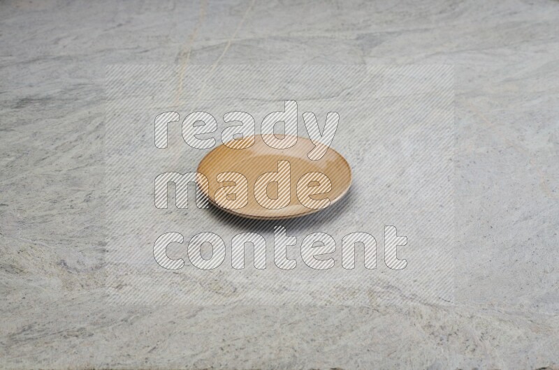 A beige pottery plate on grey marble background