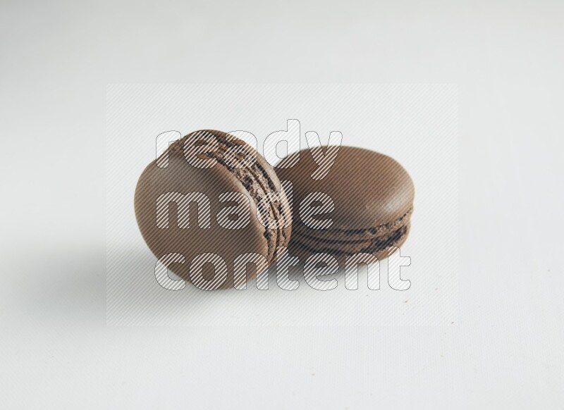 45º Shot of two Brown Dark Chocolate macarons on white background