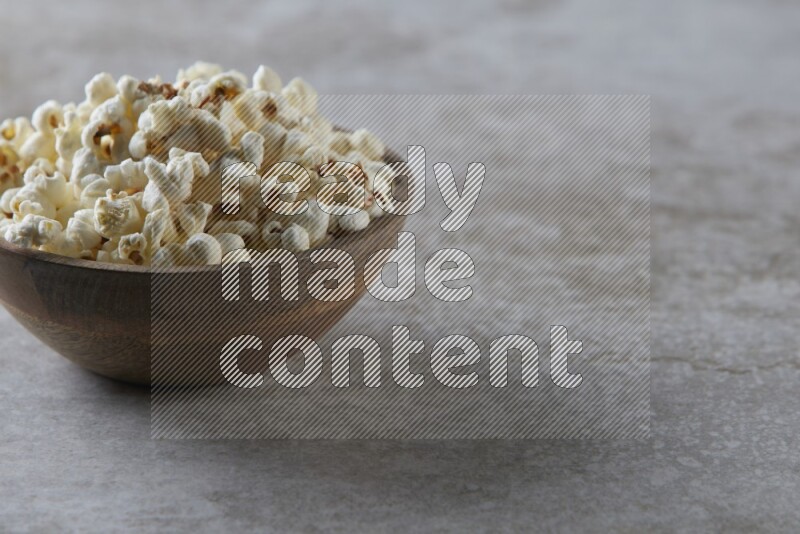 popcorn in wooden bowl on a grey textured countertop
