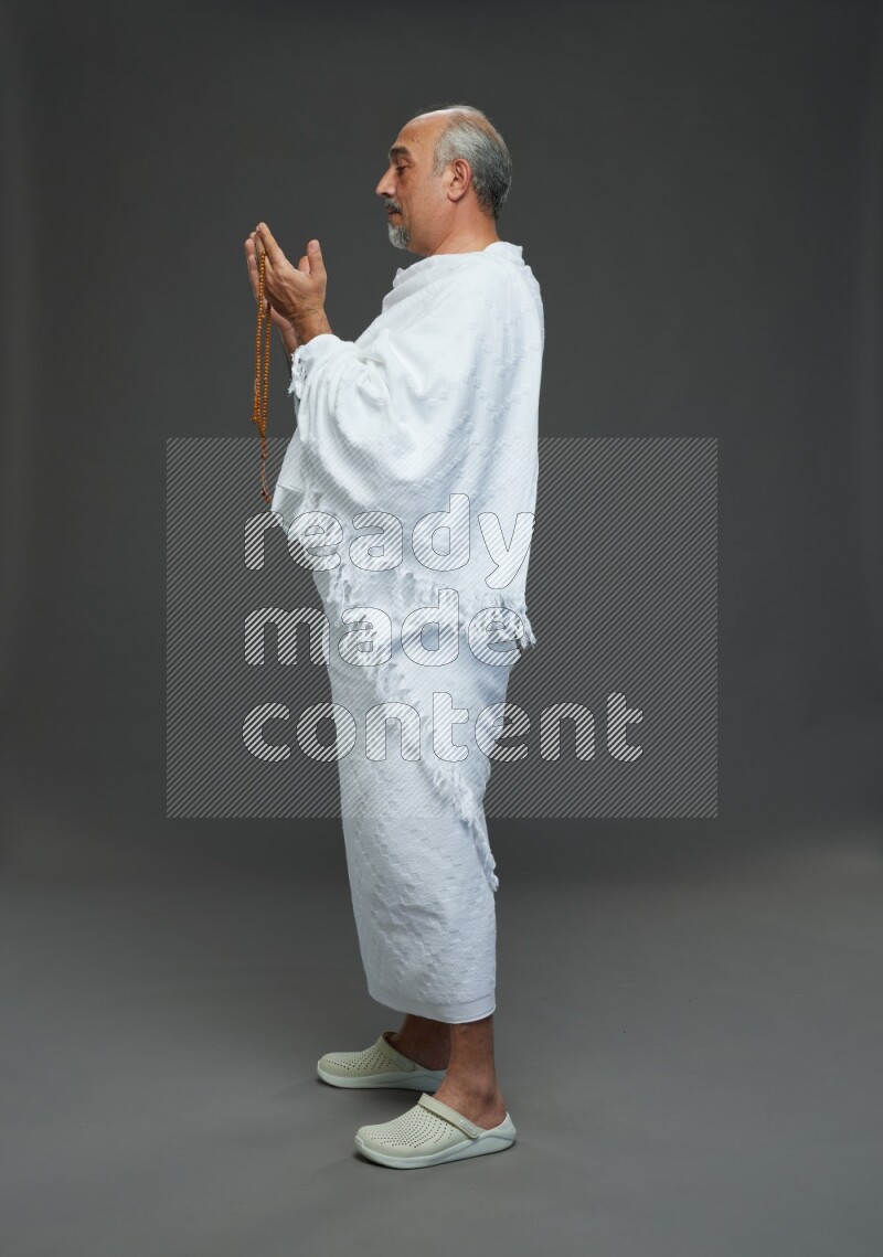 A man wearing Ehram Standing dua'a on gray background