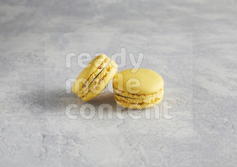 45º Shot of two Yellow Lemon macarons  on white  marble background