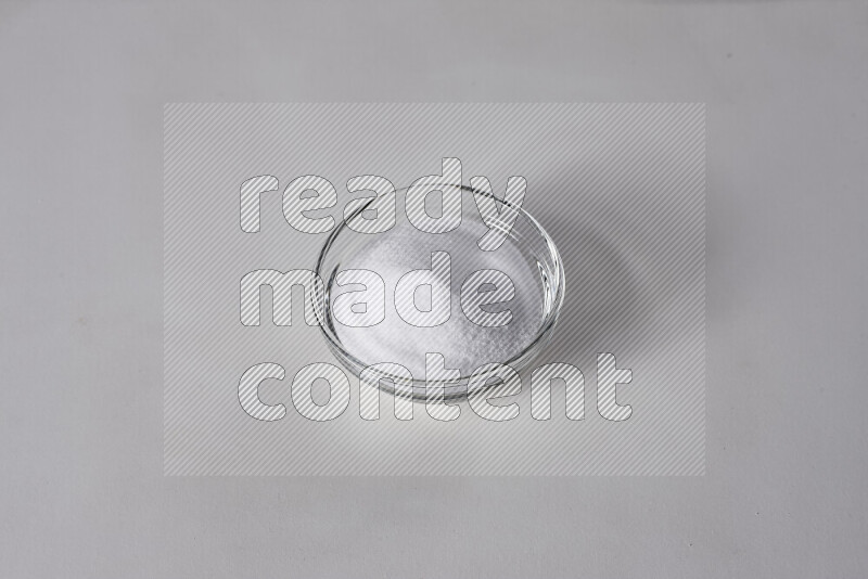 A glass bowl full of fine table salt on white background
