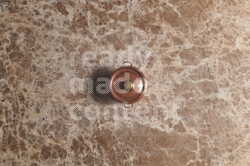 A small copper pot on beige marble background