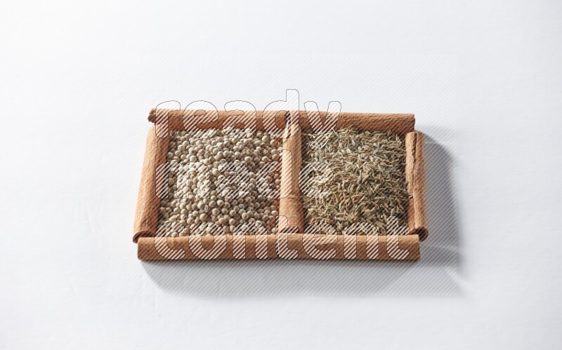 2 squares of cinnamon sticks full of white pepper and cumin on white flooring
