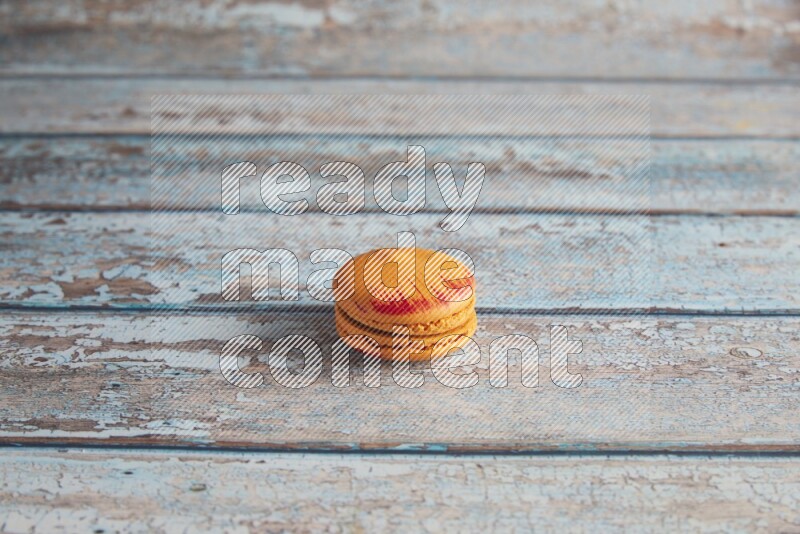 45º Shot of Orange Exotic macaron on light blue wooden background
