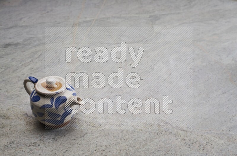A pottery teapot on grey marble background