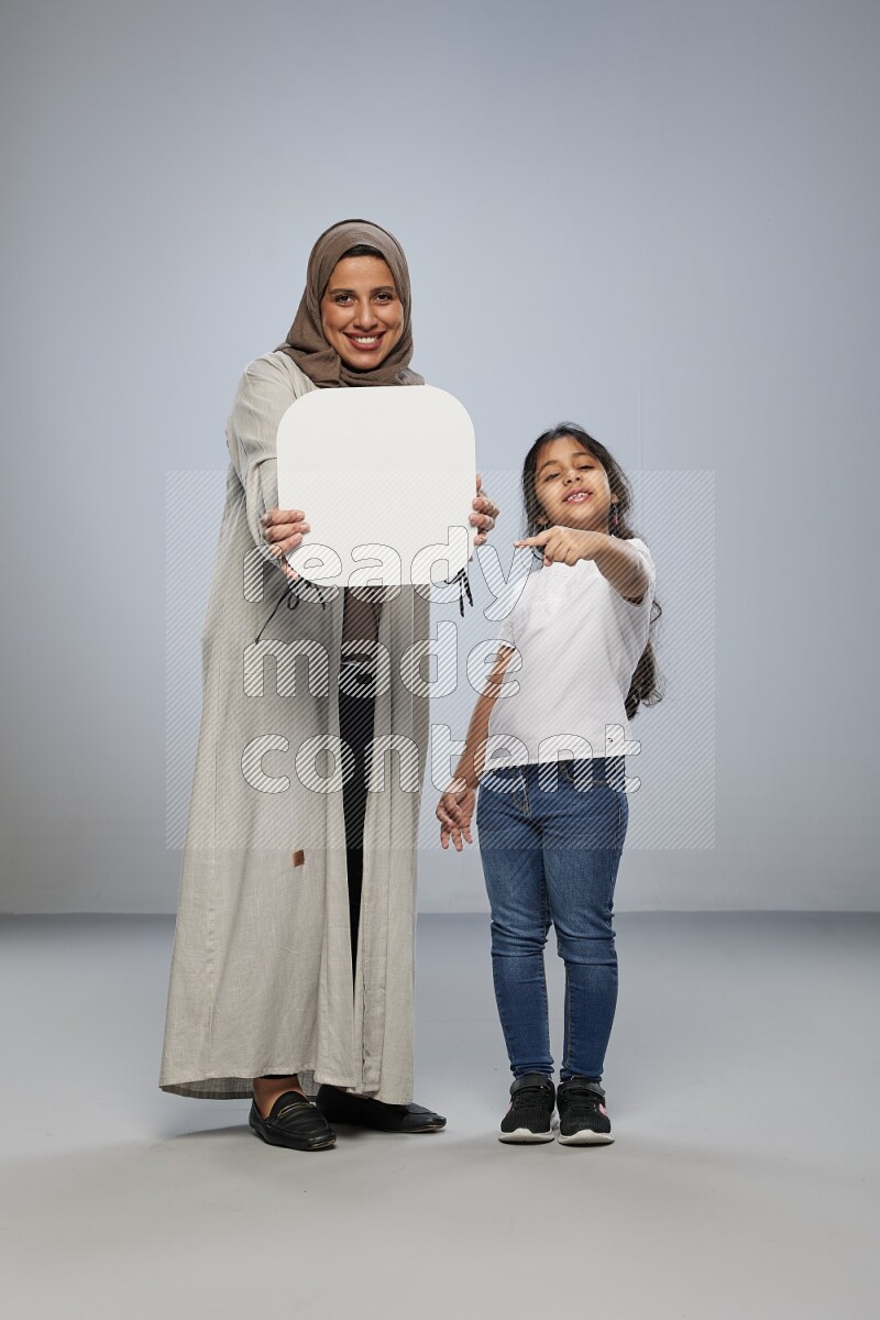 Mom and daughter standing holding social media sign on gray background