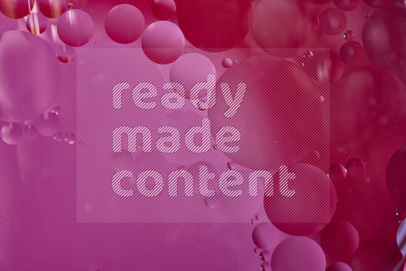 Close-ups of abstract oil bubbles on water surface in shades of red and pink