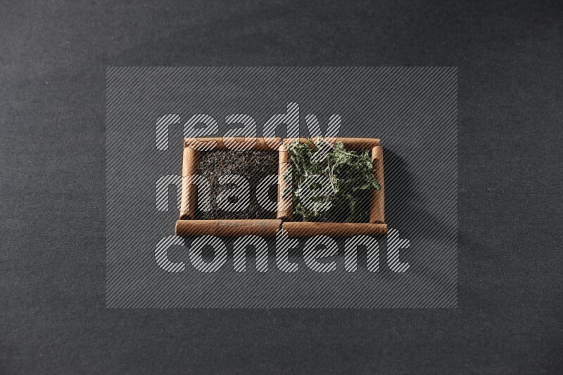 2 squares of cinnamon sticks full of tea and dried mint leaves on black flooring