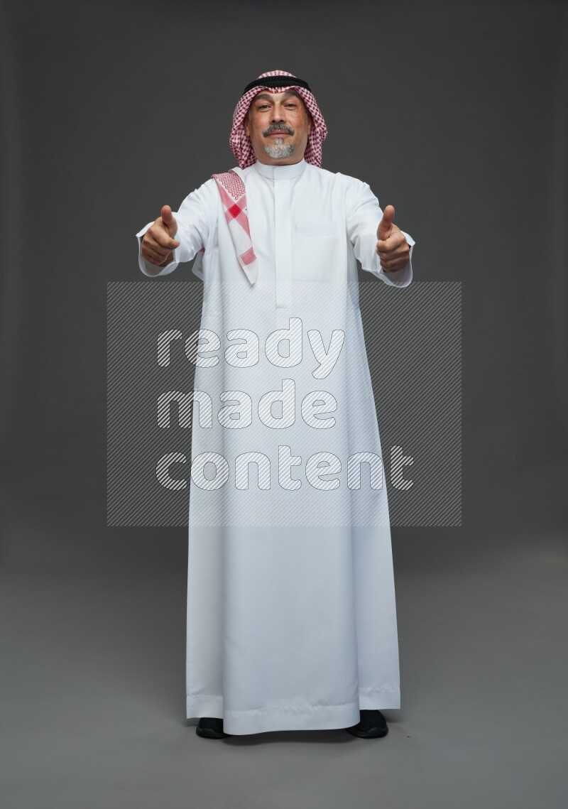 Saudi man with shomag Standing Interacting with the camera on gray background