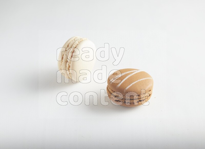45º Shot of of two assorted Brown Irish Cream, and White Caramel fleur de sel macarons on white background