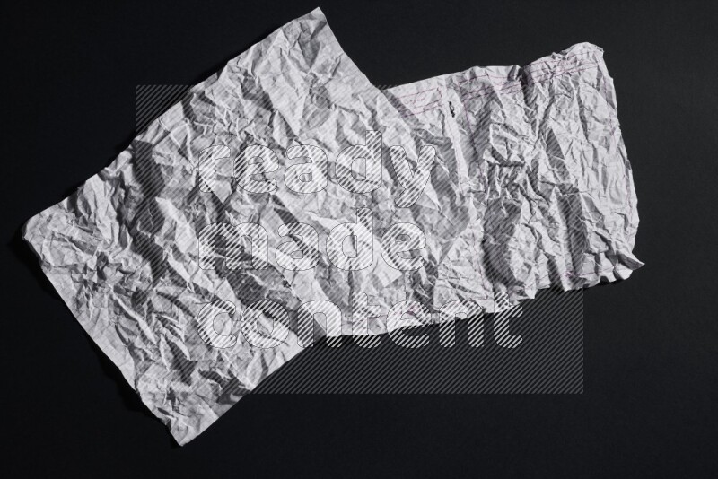 Crumpled notebook sheet on black background