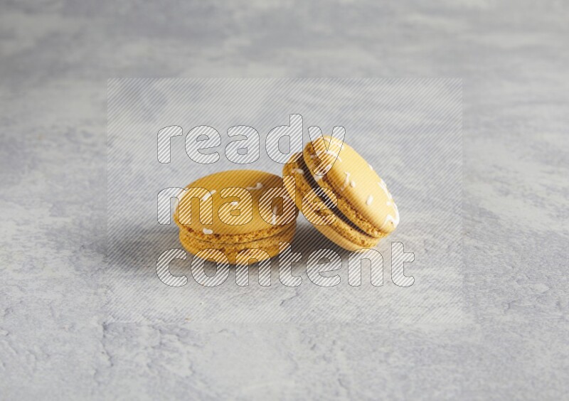 45º Shot of two Yellow Piña Colada macarons  on white  marble background