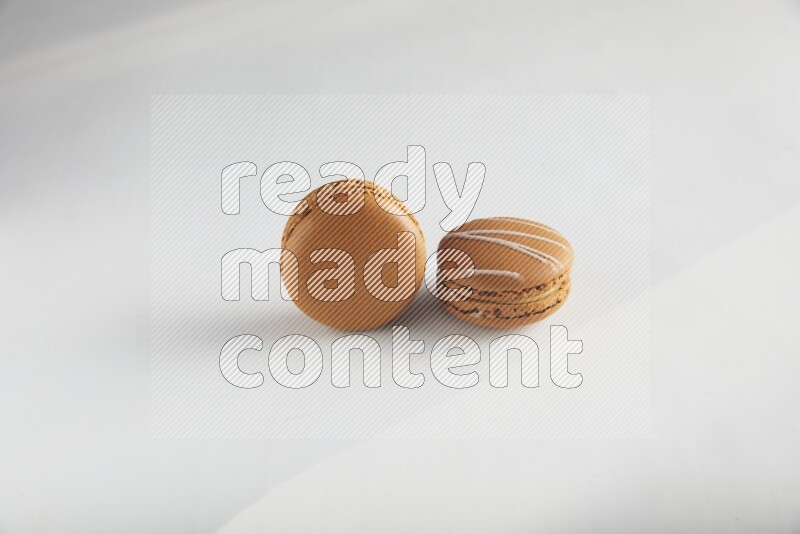 45º Shot of of two assorted Brown Irish Cream, and Brown Maple Taffy macarons  on white background