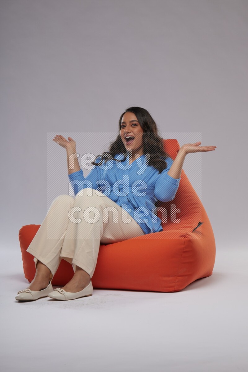 A woman sitting on an orange beanbag and interacting with the camera