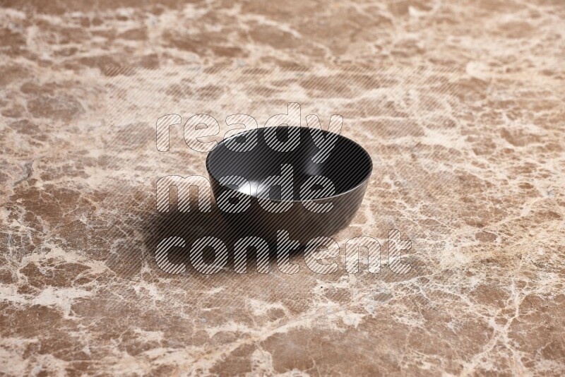 A black ceramic bowl on beige marble background