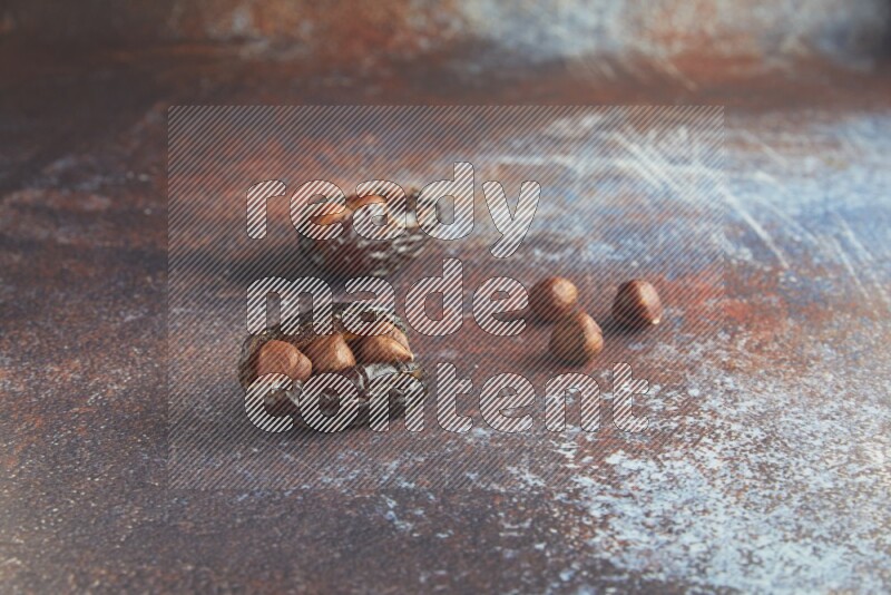 two hazelnut stuffed madjoul dates on a rustic reddish background