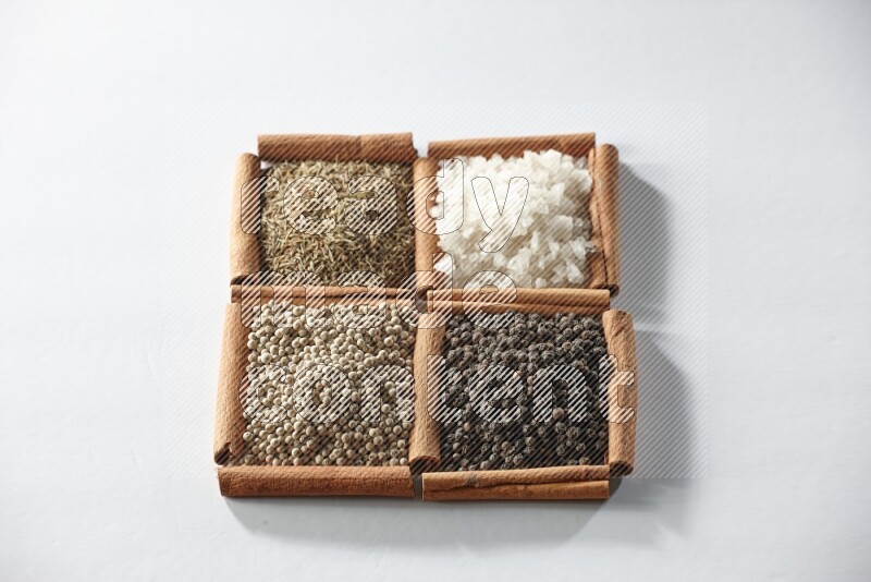4 squares of cinnamon sticks full of cumin, salt, white pepper and black pepper on white flooring