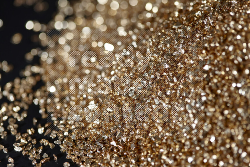 Gold shimmering fragments of glass scattered on a black background