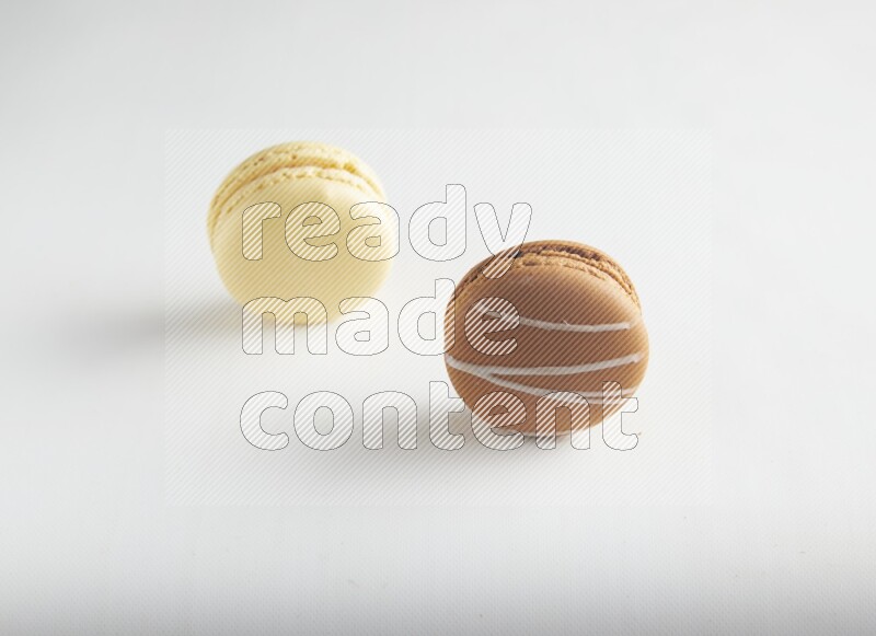 45º Shot of of two assorted Brown Irish Cream, and Yellow Vanilla macarons on white background