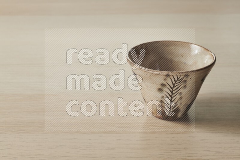 A decorative pottery bowl on light wooden background
