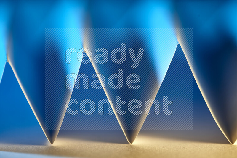 A close-up abstract image showing sharp geometric paper folds in blue gradients and warm tones