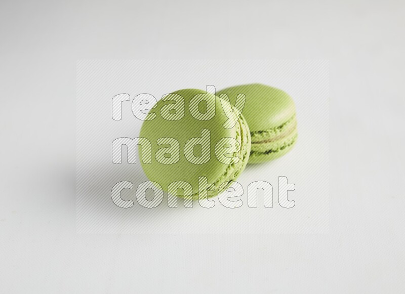 45º Shot of two Green Pistachio macarons on white background