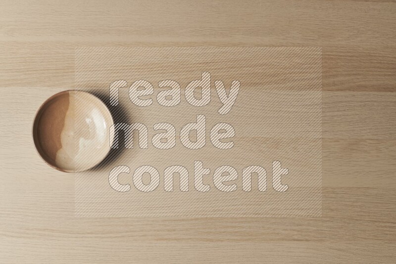 A beige pottery plate on light wooden background