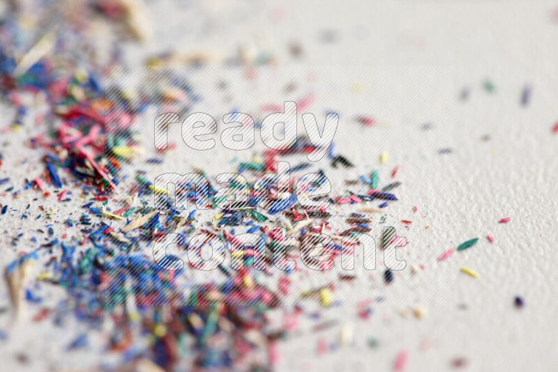 This image showcases a vibrant multicolored pencil shavings scattered on grey background