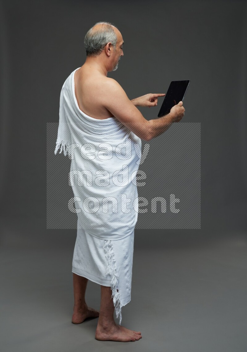 A man wearing Ehram Standing working on tablet on gray background